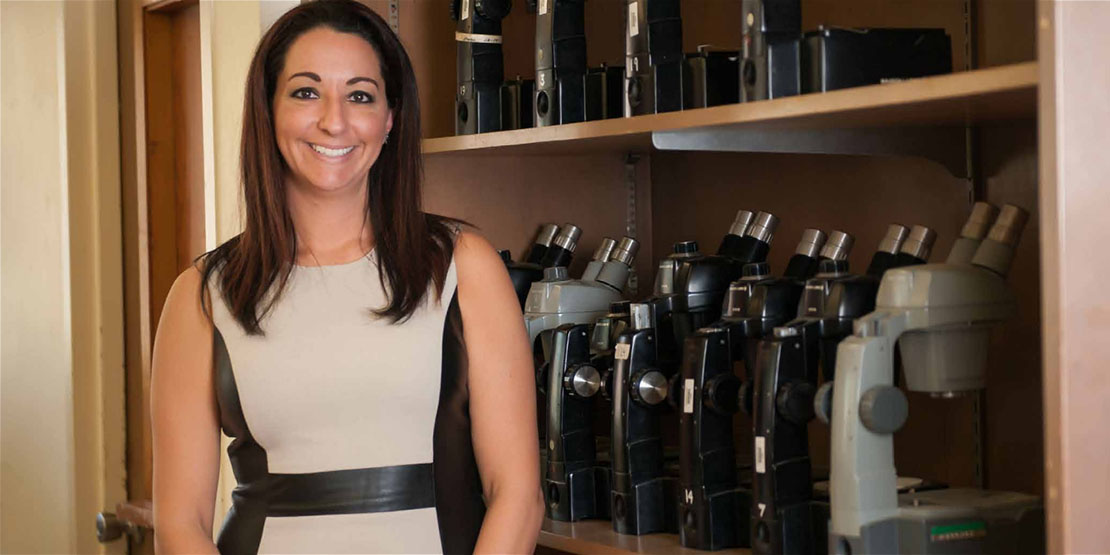 Michelle Miranda in front of a wall of microscopes