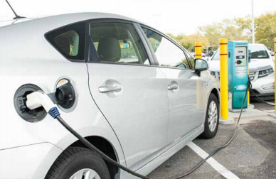 Close-up of a white electric vehicle being charged in a FSC parking lot