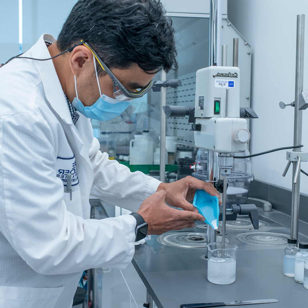 Technician pouring powder into a beaker in a lab