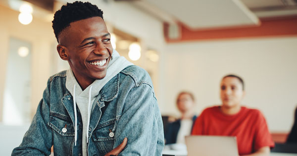 Student in a denim jacket sitting in a classroom smiling